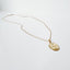 A delicate gold chain necklace with a small, oval gold Mother Mary pendant.