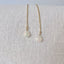 Pair of gold earrings with heart-shaped opal stones on a light gray fabric background