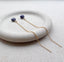 Gold threader earrings with blue sapphire gemstones on a white stone surface