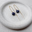 Gold threader earrings with blue sapphire gemstones on a stone surface
