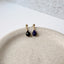 Pair of teardrop-shaped sapphire earrings on a textured surface