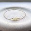 Gold bracelet with three white opal beads on a textured white surface