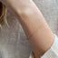 A dainty gold cable chain bracelet displayed on a model