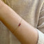 Gold bracelet with a red garnet beads on a person's wrist against a neutral background