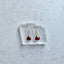 Gold earrings with red garnet gemstones on a clear stand against a light gray background