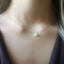 Necklace with a opal pendant worn by a person, focusing on the jewelry.