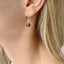Close-up of a person wearing a red garnet earring with a blurred background