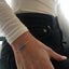 Hand wearing a gold bracelet with blue turquoise beads on a blurred background