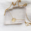 Gold necklace with a yellow citrine gemstone on a clear crystal block