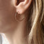 Gold hoop earring worn by a person with blonde hair.