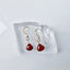Red garnet earrings on a clear stand with a white background