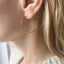 Close-up of a gold hoop earring worn by a person with blonde hair.