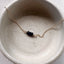 Gold necklace with sapphire beads in a ceramic dish
