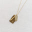 Gold necklace with two rectangular pendants and citrine beads on a textured white background