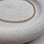product shot showing a dainty gold rolo chain lying in a stoneware dish