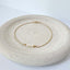 Three strand pearl bracelet with freshwater pearls on a delicate gold chain, minimalistic design on a round dish.