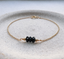 Black onyx gold chain bracelet on a ceramic dish