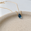 Close-up of a faceted London blue topaz briolette wire-wrapped on a 14k gold-filled cable chain