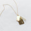 Gold necklace with two pendant charms and citrine on a light gray background