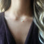 Necklace with a small opal pendant worn by a person with blonde hair.