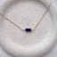 Gold necklace with blue beads on a stone surface