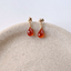 Carnelian teardrop stud earrings in 14k gold-filled on a ceramic dish