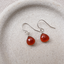 Carnelian heart drop earrings in sterling silver on a speckled ceramic dish