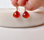 Hand holding faceted carnelian heart drop earrings on 14k gold-filled French ear wires