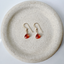 Carnelian drop earrings in 14k gold-filled centered on a round speckled ceramic plate