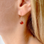 Close-up of a carnelian heart drop earring in 14k gold-filled worn on the ear