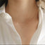 Model shown wearing a dainty gold open heart charm necklace.