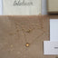 Gold citrine necklace on a brown surface with 'lolabean' branding in the background