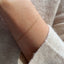 A dainty gold curb chain bracelet displayed on a model