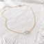 Faceted aquamarine bead necklace laid flat on a fringed linen napkin