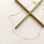 Cubic zirconia station necklace draped over an antique brass cross on linen