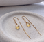 Delicate gold citrine paperclip threader earrings on a stone dish