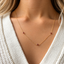 Dainty garnet station necklace worn on the collarbone with a white sweater