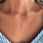 Close-up of a dainty gold vertical bar necklace with four white opal beads off-center on the chain