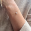 Delicate gold bracelet with an opal teardrop charm worn with a knit sweater
