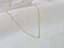 Tiny freshwater pearl on a delicate gold-filled cable chain on white linen