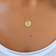 Close-up of a gold-filled initial disc with citrine teardrop worn on the neck, November birthstone