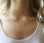 Dainty gold cubic zirconia station necklace worn on the collarbone with a white tank top