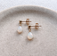 Gold opal teardrop earrings on a stone dish