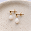 Pair of gold opal teardrop earrings on a ceramic dish