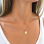 Gold initial disc necklace with citrine charms worn on the collarbone with a white tank top