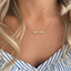 Delicate opal bead bar necklace worn with a striped blouse