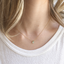 Model wearing a dainty prehnite teardrop necklace in 14k gold-filled with a white tee