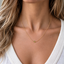 Tiny peridot bead necklace in gold filled worn at the collarbone with a white V-neck top