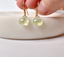 Hand holding faceted prehnite heart drop earrings on 14k gold-filled French ear wires