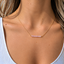 Model wearing a rose quartz beaded bar necklace in 14k gold filled at the collarbone